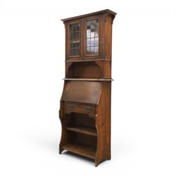 Arts & Crafts oak bureau bookcase, projecting cornice with leaded and glazed upper cabinet, the lower section with fall front section revealing a fitted interior, above shaped lower shelving 