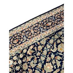 Persian Kashan indigo ground rug, the field consisting of trailing flower head bands and leafy branches, decorated with kuş or bird motifs, the border with repeating border containing curling leaves and flower heads, within guard bands 