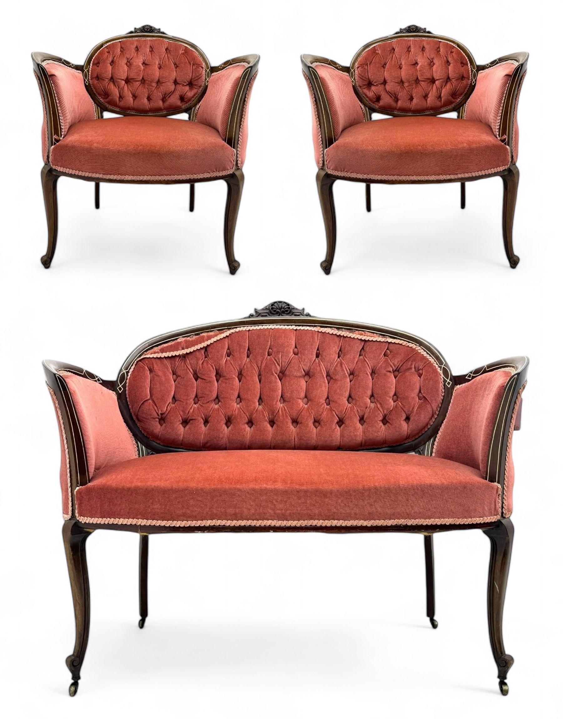 Edwardian inlaid rosewood parlour suite, comprising pair of tub shaped armchairs (W77cm, D69cm, H88cm); and matching two-seat sofa (W112cm, D69cm, H88cm), each with carved crest rails with shell motifs, deep button-tufted oval backs upholstered in pink fabric with braid trim, on cabriole supports