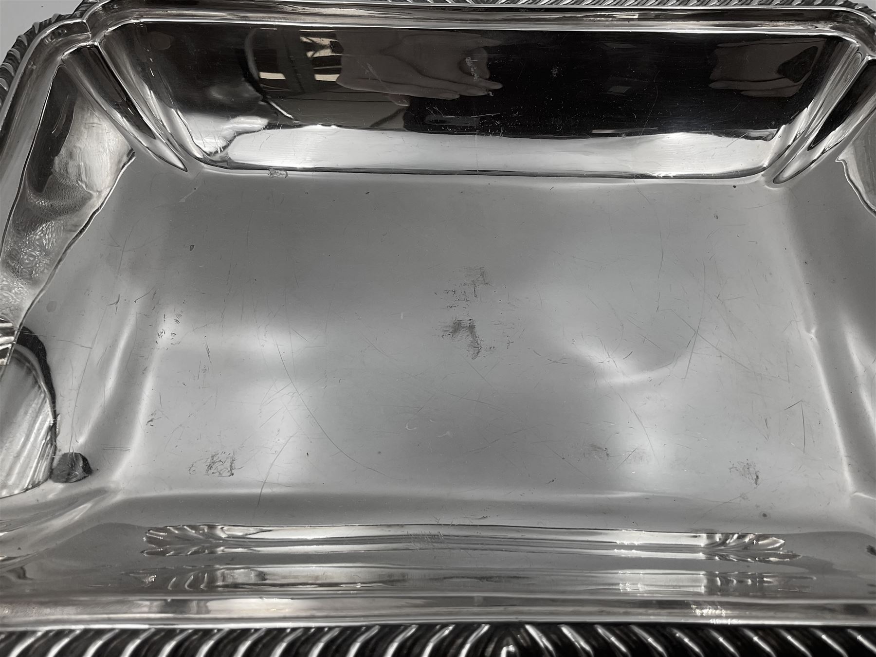 Early 20th century silver entree dish and cover, of rectangular form with shaped corners and oblique gadrooned borders to base and cover, the cover with loop 'bamboo' handle, hallmarked Thomas Bradbury & Sons Ltd, Sheffield 1930, including handle H10.5cm L24.5cm