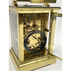 Early 20th century brass and bevelled glass repeater carriage clock with alarm, the angular and cylindrical ribbed handle and repeater button over stepped cavetto cornice, white enamel Roman dial with Arabic subsidiary alarm set dial, twin train eight day movement striking the hours and half on coil, separate alarm mechanism train, stepped moulded and plain faced base, with leather travelling case