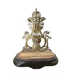 English-Late 19th century 8-day Skeleton clock on an oval ebonised base c1880, with pierced brass plates and silvered chapter ring, Roman numerals and gothic trefoil hands, chain driven five-pillar fusee movement and pierced mainspring barrel cap, timepiece movement with key and pendulum. 