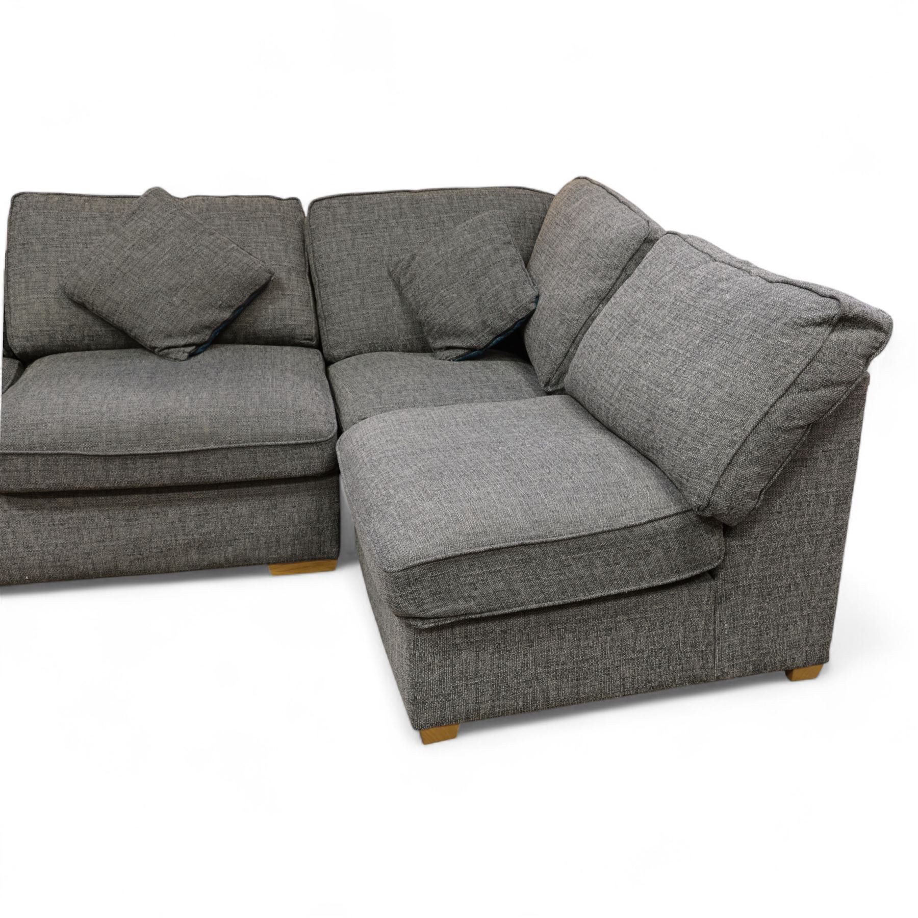 Contemporary grey fabric corner sofa and ottoman, comprising modular sections with removable back and seat cushions, raised on light wood block feet