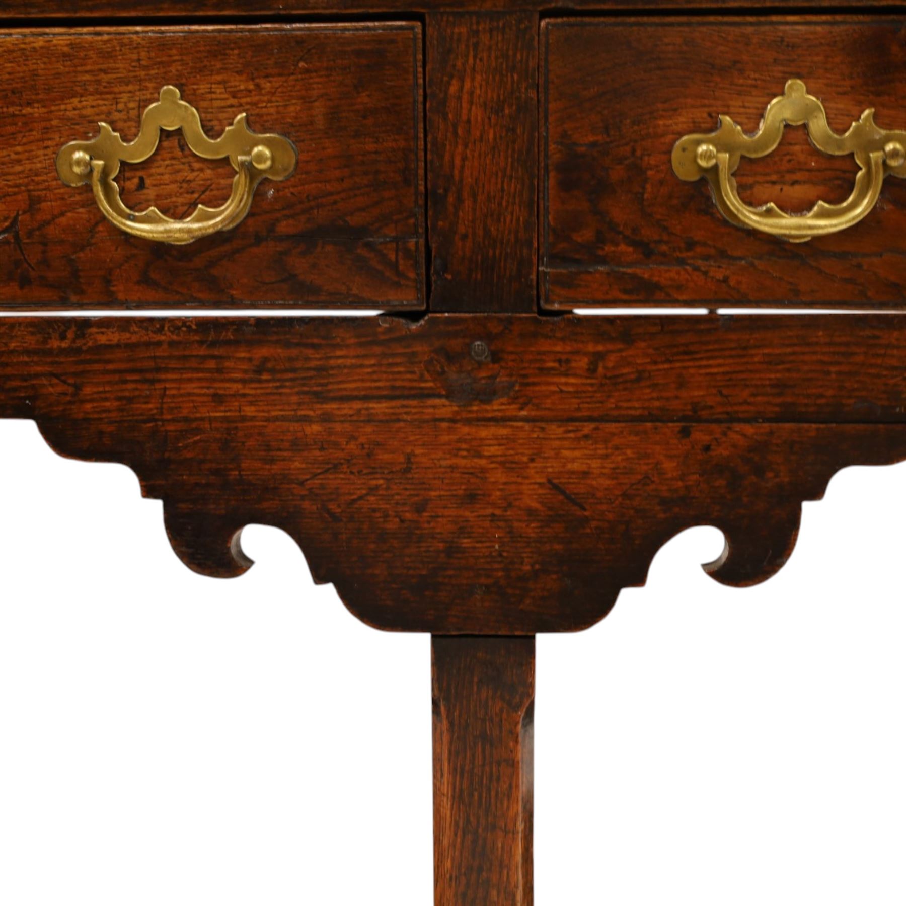 George III oak dresser base, rectangular top with moulded edge, fitted with two drawers over shaped spandrels, raised on square chamfered supports united by undertier, on stile feet