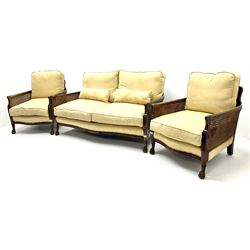 Early 20th century mahogany framed Bergere settee, double cane sides with acanthus carved arms on hairy paw feet, upholstered in a pale gold fabric (W145cm) and two matching armchairs (W66cm)