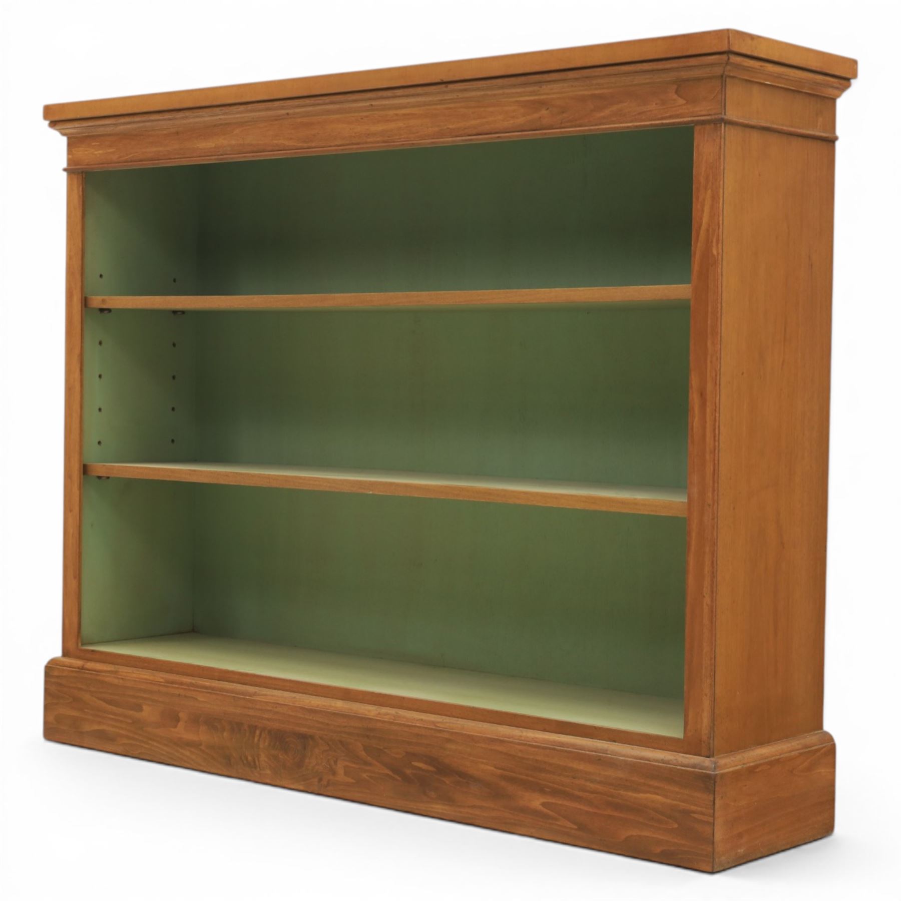 Traditional walnut small bookcase, with projecting cornice above a green painted interior, adjustable shelving, on a moulded plinth base