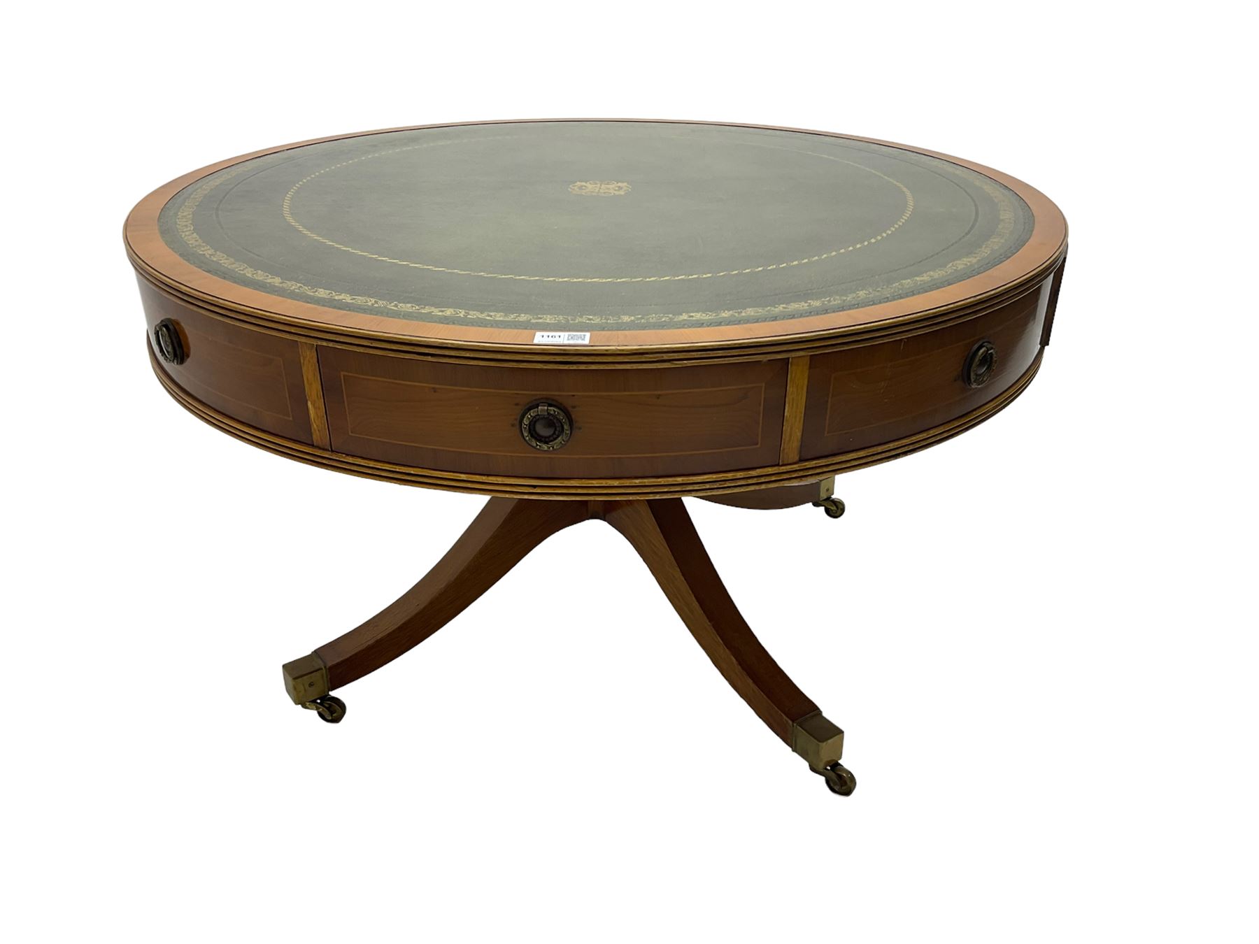 Georgian style yew wood drum table, circular top with green and tooled leather inset, fitted with four drawers, on turned pedestal base with four splayed supports, brass cups and castors
