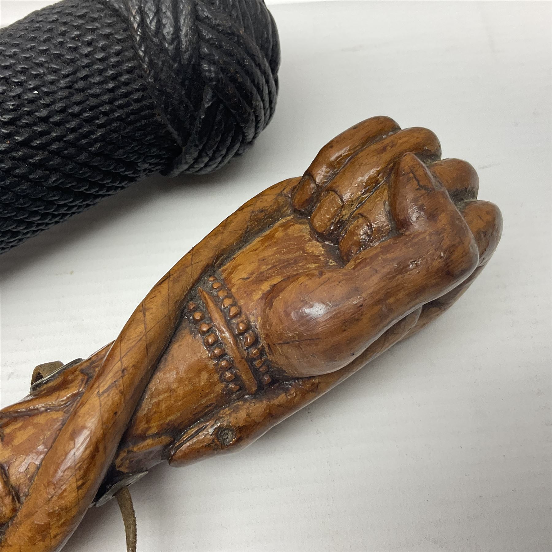 19th century wooden walking stick, the handle carved as a snake within a clenched fist, the cane carved with foliate and cross hatched decoration, with a metal spike to base, together with a turned wooden walking stick, with lacquered rope nautical knot handle, tallest L96.5cm
