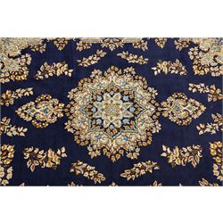 South East Persian Kirman hand-knotted carpet, indigo blue field with central floral medallion in tones of ivory, indigo,  and soft blue, issuing network of scrolling vinery, palmettes and floral sprays, conforming spandrels, broad main border of scrolling foliage and stylized palmettes, framed by multiple guard borders, with cotton fringe ends 