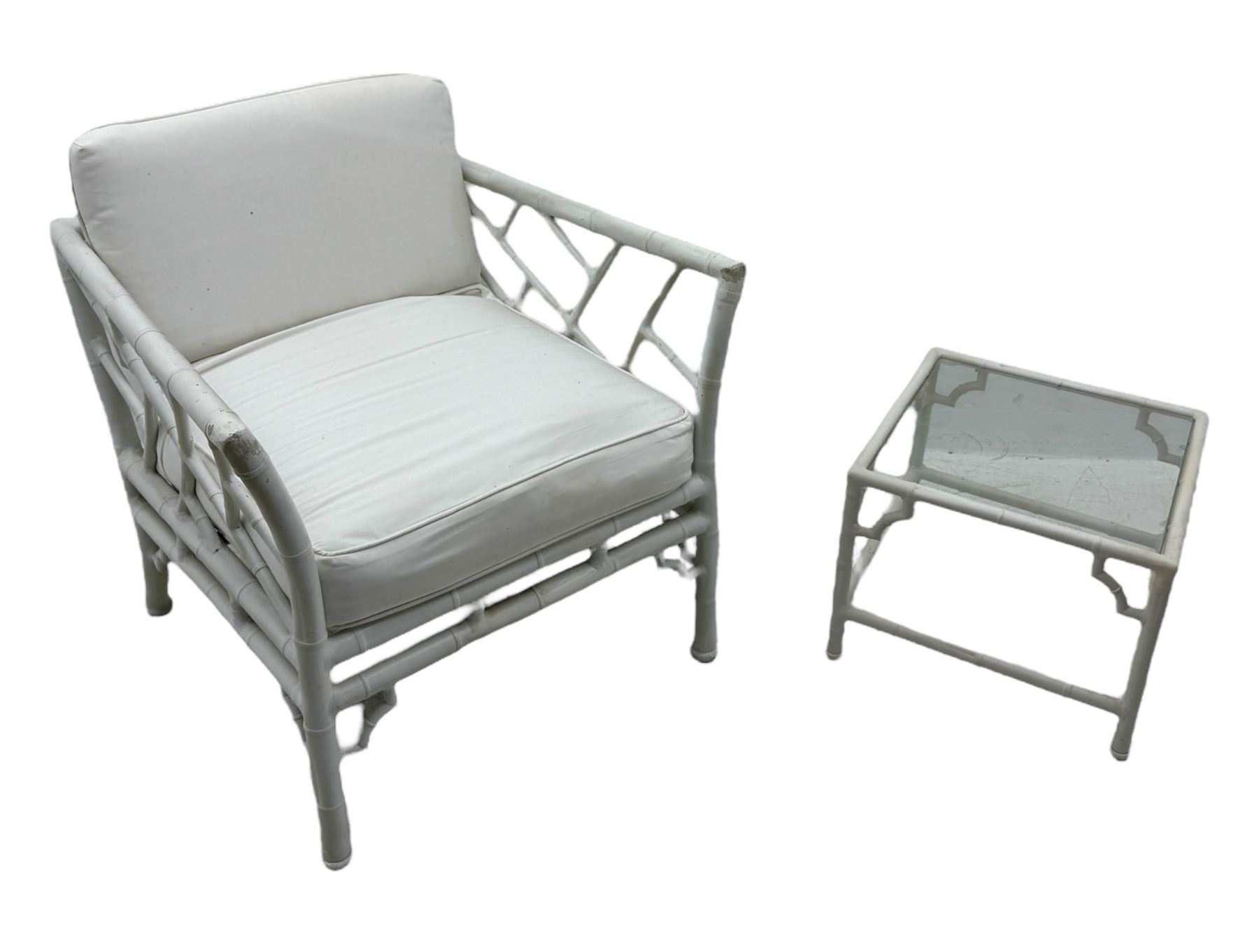 Late 20th century faux bamboo conservatory sofa, white painted frame with geometric openwork back and sides, loose cream cushions, on cylindrical supports (W134cm, D76cm, H80cm); matching armchair (W75cm, D76cm, H80cm); matching coffee table with glass insert (W46cm, D45cm, H36cm)
