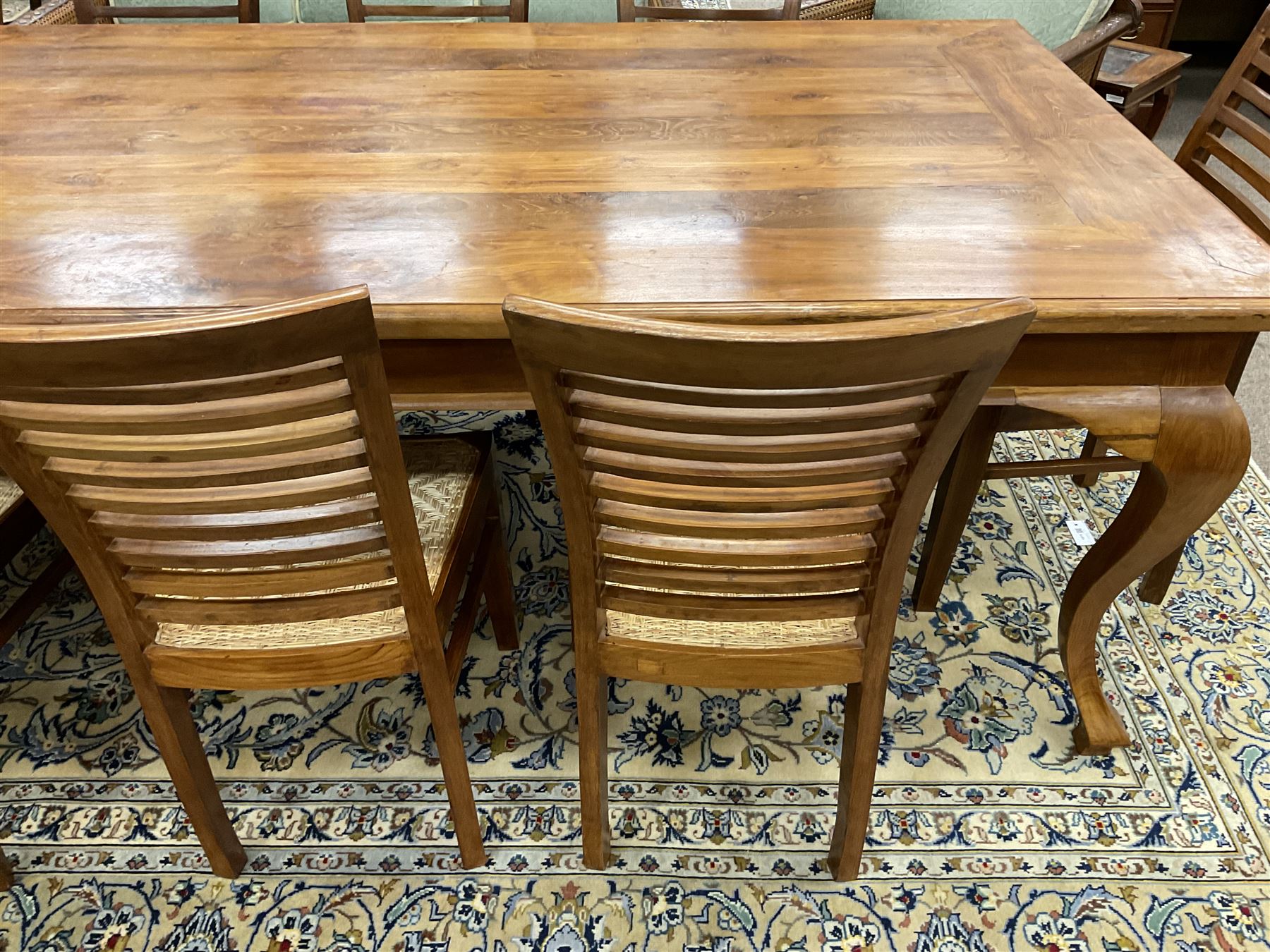 Large teak dining table, moulded rectangular top, on cabriole supports, together with a set of ten ladder back dining chairs with cane work seats