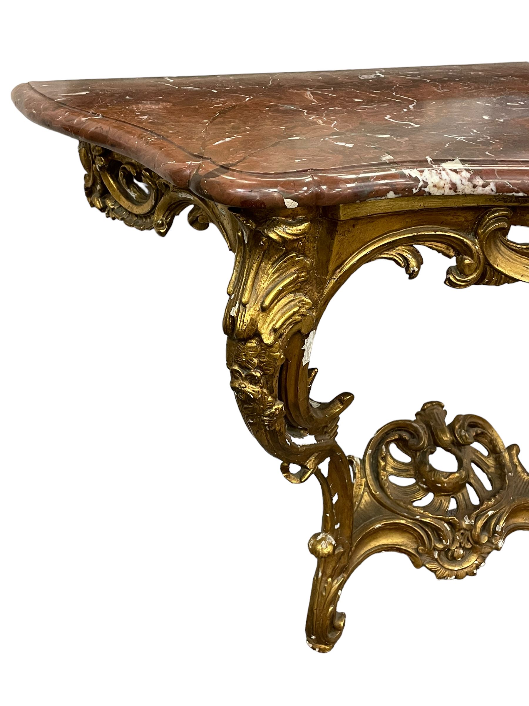 19th century giltwood and gesso console table, shaped variegated rouge marble top with moulded edge, central shell motif with extending scrolled foliage, on foliate and flower head moulded cabriole supports united by pierced shell middle rail, scrolled acanthus leaf terminals 
