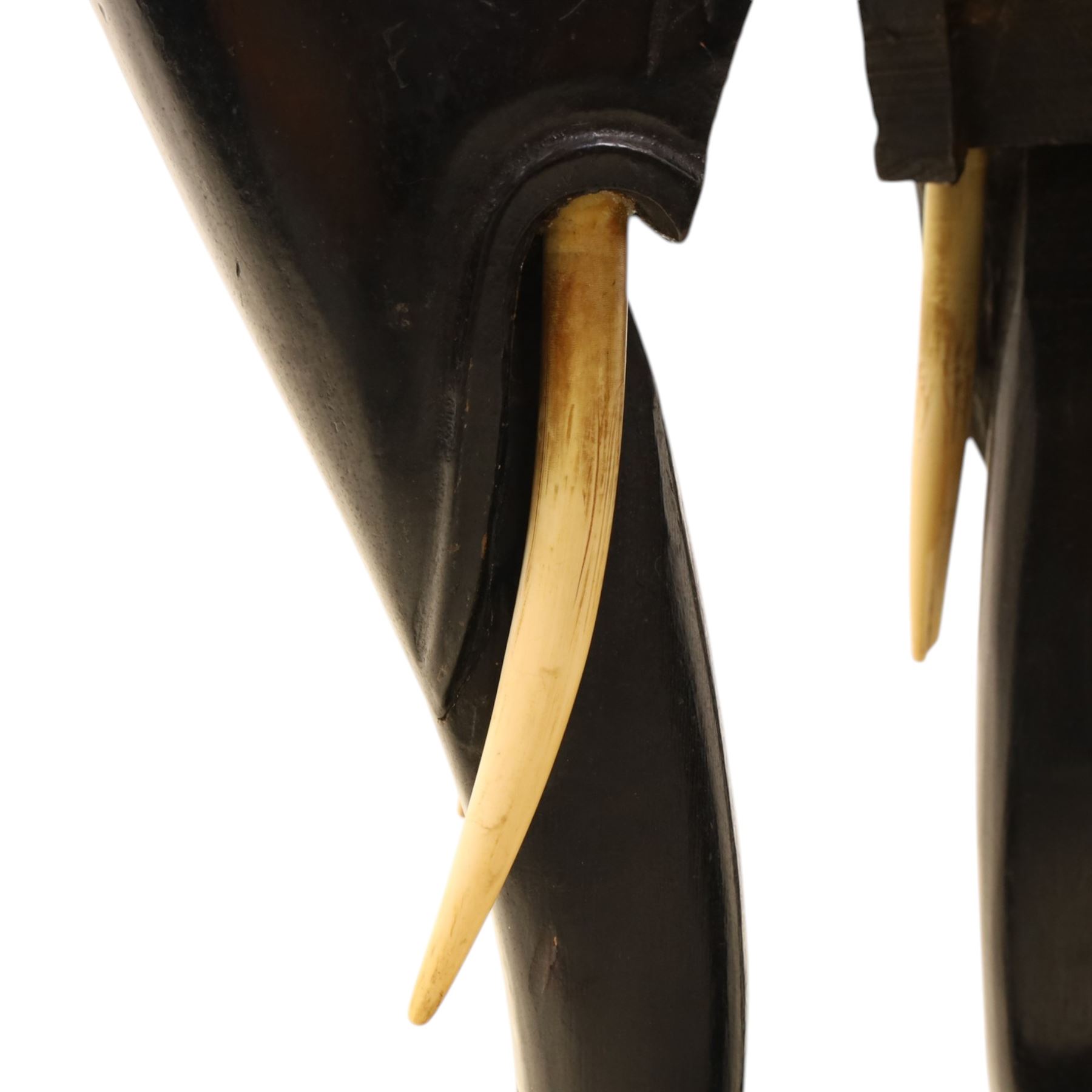 Oriental design black lacquered jardinière stand, circular moulded top with raised rim, the base formed as three elephant heads with carved ears and simulated tusks, on shaped supports with paw terminals