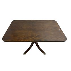 Regency mahogany breakfast table, rectangular banded tilt-top on turned column with four splayed supports, brass castors