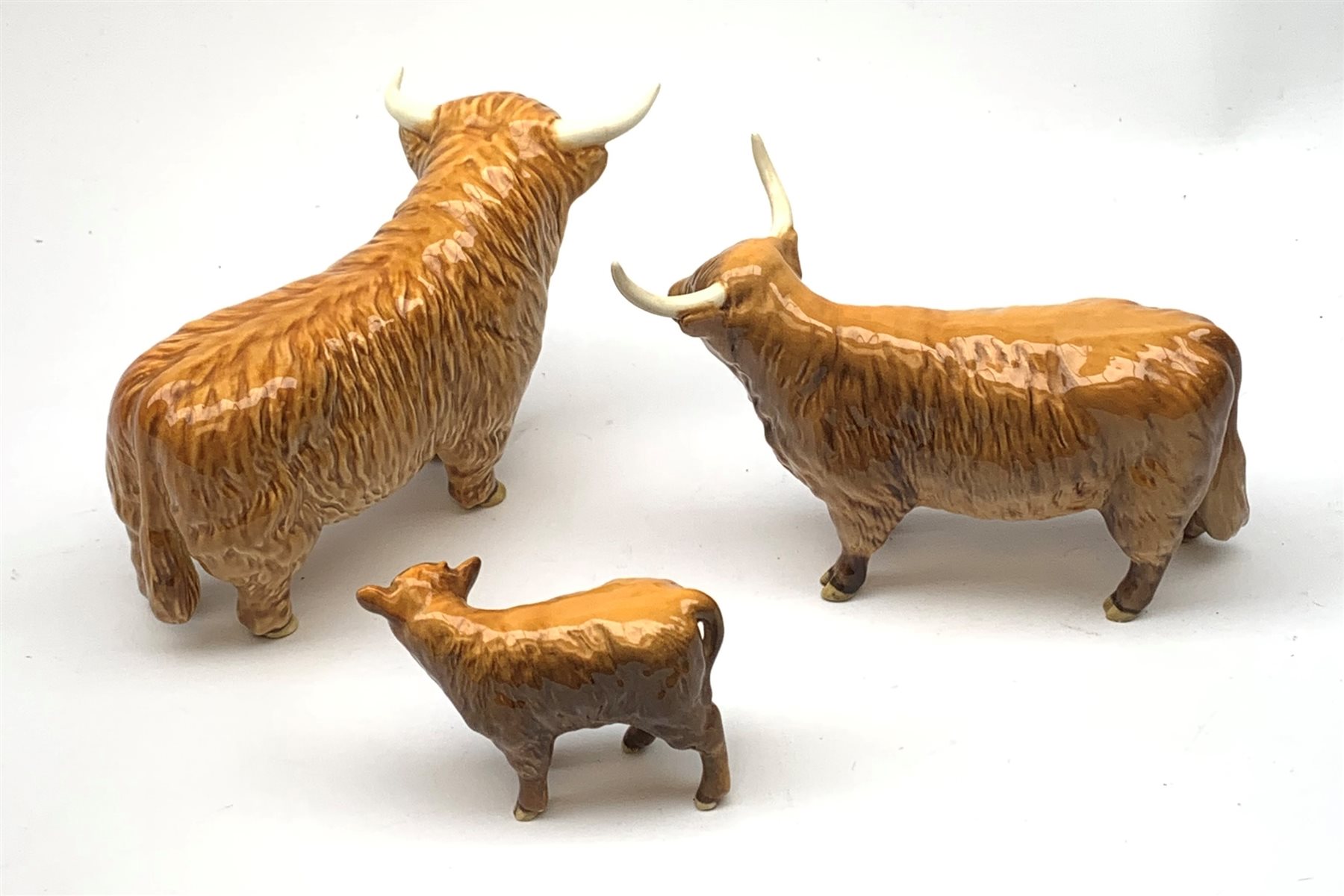 A Beswick Highland Bull, Highland Cow, and Highland Calf, each with printed mark beneath. 