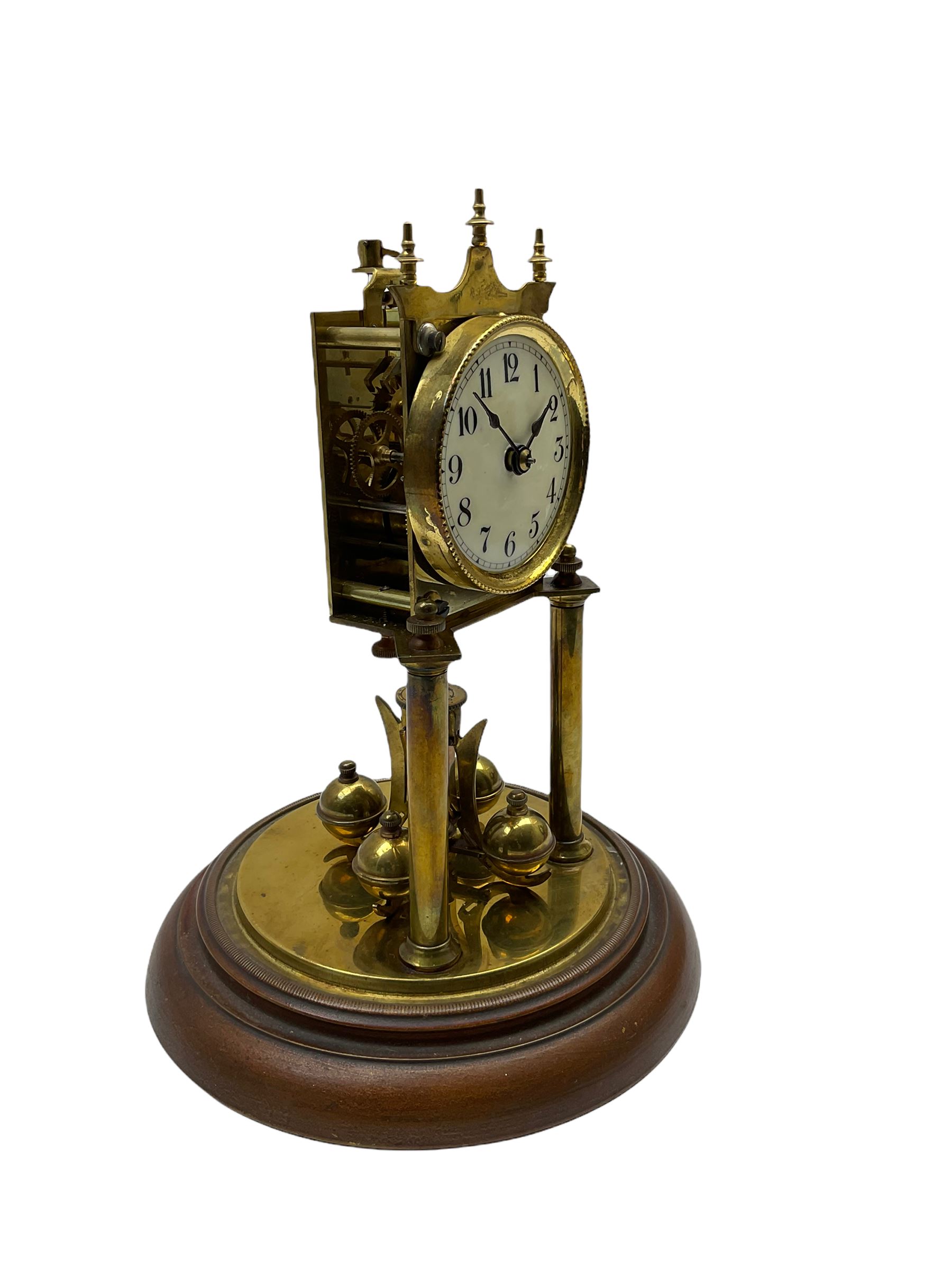 A German torsion pendulum clock by  Jahresuhrenfabrik (August Schatz & Söhne), Triberg, Germany, early 20th century with a three-inch cream enamel dial within a spun bezel, upright Arabic numerals with minute track and steel spade hands, 400-day spring driven movement with a four-ball rotary pendulum, clear glass dome on an 8” circular brass effect base.

