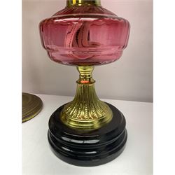 Victorian cast brass oil lamp, with fluted pink glass shade, together with two smaller brass oil lamps with pink shades and reservoirs and a pair of oil lamps, the bases modelled as putti, with pink glass reservoir  and frosted shades, tallest H70cm