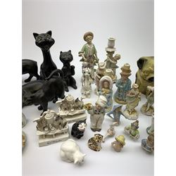 A collection of various ceramic figurines, to include pair of small 19th century Staffordshire cats, Royal Doulton cat, Coalport cat, pair of 19th century pug dogs, two fairings inscribed Good Templars, two Bonzo dog peppers, a number of pin cushion dolls, various 20th century and later black pottery cats, Victorian bisque figures, etc. 