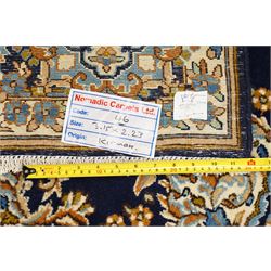South East Persian Kirman hand-knotted carpet, indigo blue field with central floral medallion in tones of ivory, indigo,  and soft blue, issuing network of scrolling vinery, palmettes and floral sprays, conforming spandrels, broad main border of scrolling foliage and stylized palmettes, framed by multiple guard borders, with cotton fringe ends 