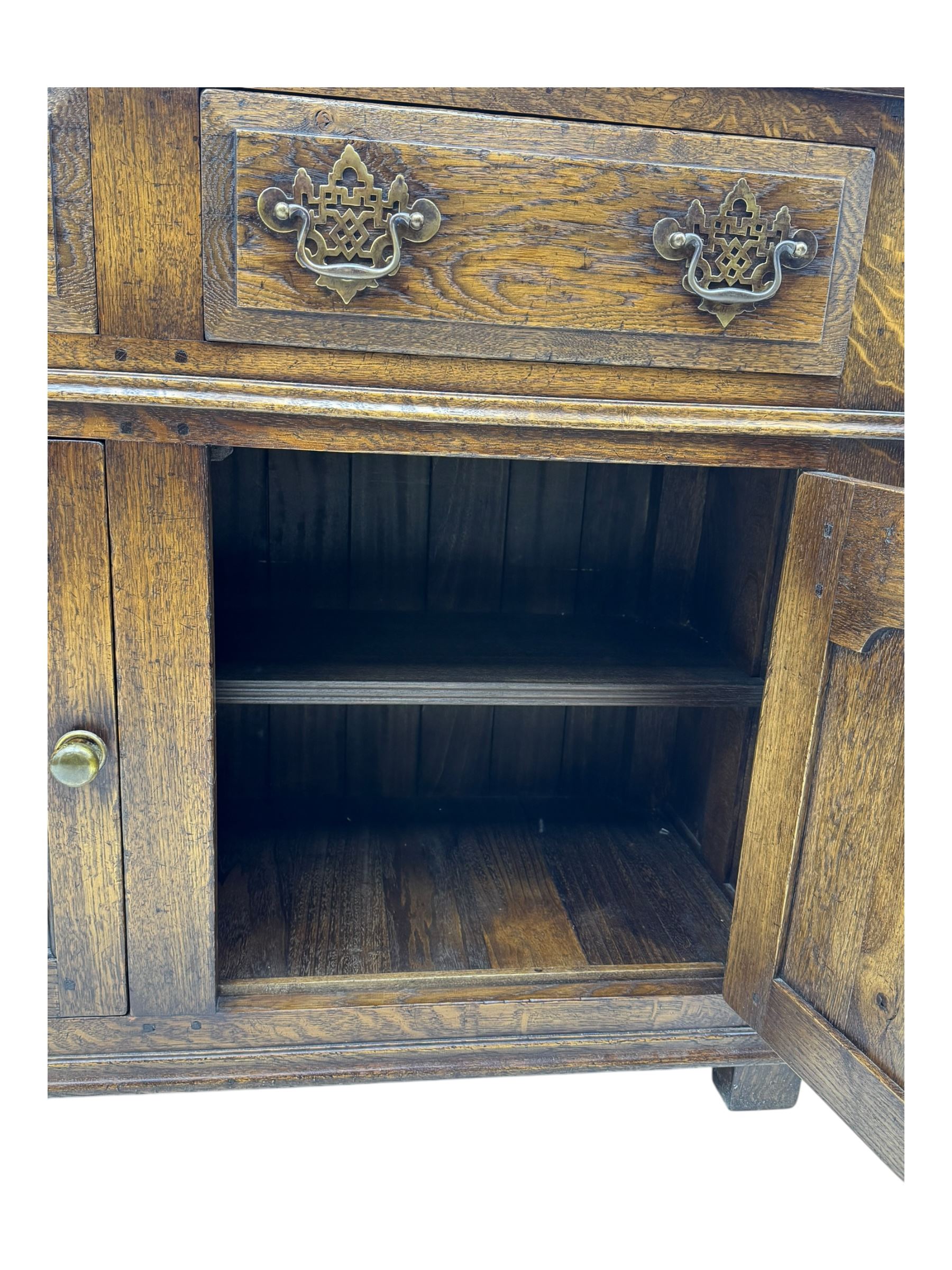 Early 20th century Jacobean design oak dresser sideboard, rectangular top with moulded edge over two baize-lined drawers with pierced handles, above two fielded panel cupboard doors, on stile supports
