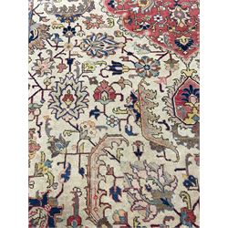 Persian carpet, pale ground with floral medallion, the field decorated with stylised plant motifs, geometric interlacing, the guarded border with repeating flower head design