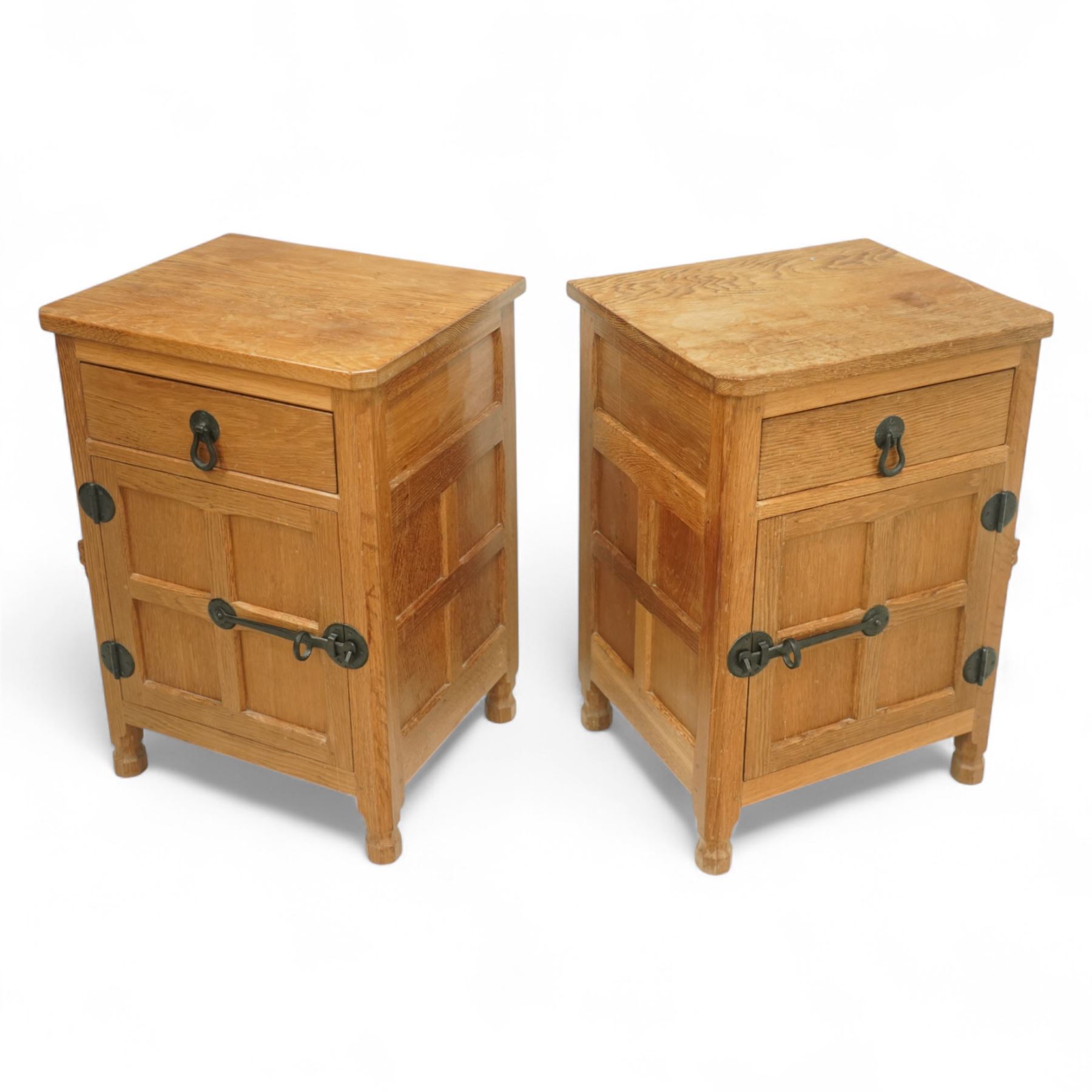 Beaverman - pair of oak bedside cabinets, each with plain rectangular top over single drawer and cupboard below with fielded panels and wrought iron hardware, with signature carved beaver, by the workshop of Colin Almack, Thirsk