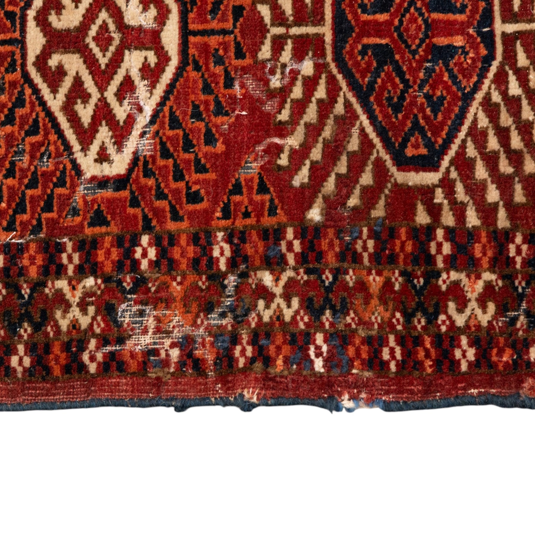 Persian Bokhara crimson ground rug, the field decorated with five rows of repeating Gul motifs with interspersed geometric design, enclosed by a guard band of further geometric-style Gul designs comprised of hook motifs