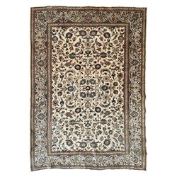 Persian Kashan ivory ground carpet, the field decorated with scrolling branches with foliate and palmette motifs, repeating border with stylised plant motifs, within floral and geometric pattern guard stripes 