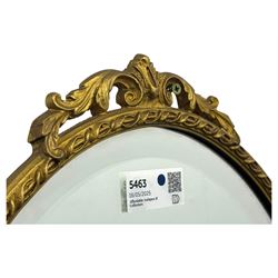 Oval gilt wall mirror, with bevelled edge plate within a moulded frame cast with acanthus scrolls and foliate decoration, pierced cartouche crest and apron, flanked by scrollwork handles