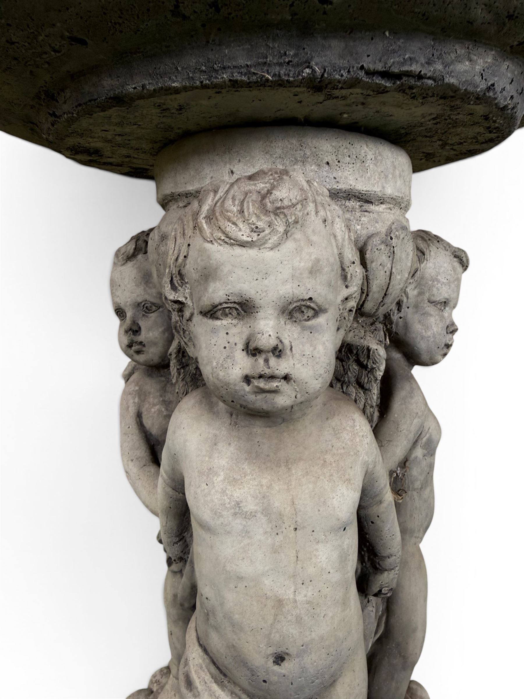 Cast stone cherub bird bath, circular removable top raised on three cherubs with ornate detailing