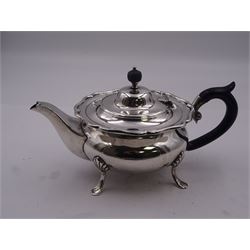 Early 20th century silver bachelors teapot, of squat circular form with shaped rim, and ebonised handle and finial, upon four pad feet, with engraved dedication to underside, hallmarked William Hutton & Sons Ltd, Sheffield 1912, approximate gross weight 12.71 ozt (395.3 grams)
