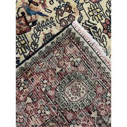 Persian Hamadan rug, ivory ground and decorated profusely with stylised plant, flower and bird motifs, triple band border decorated with stylised flower heads