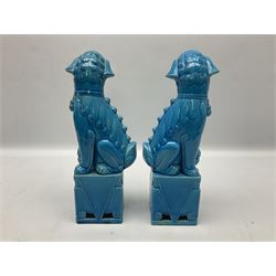20th century pair of blue glazed Foo Dog statues raised upon a square plinths, together with a similar green resin foo dog
