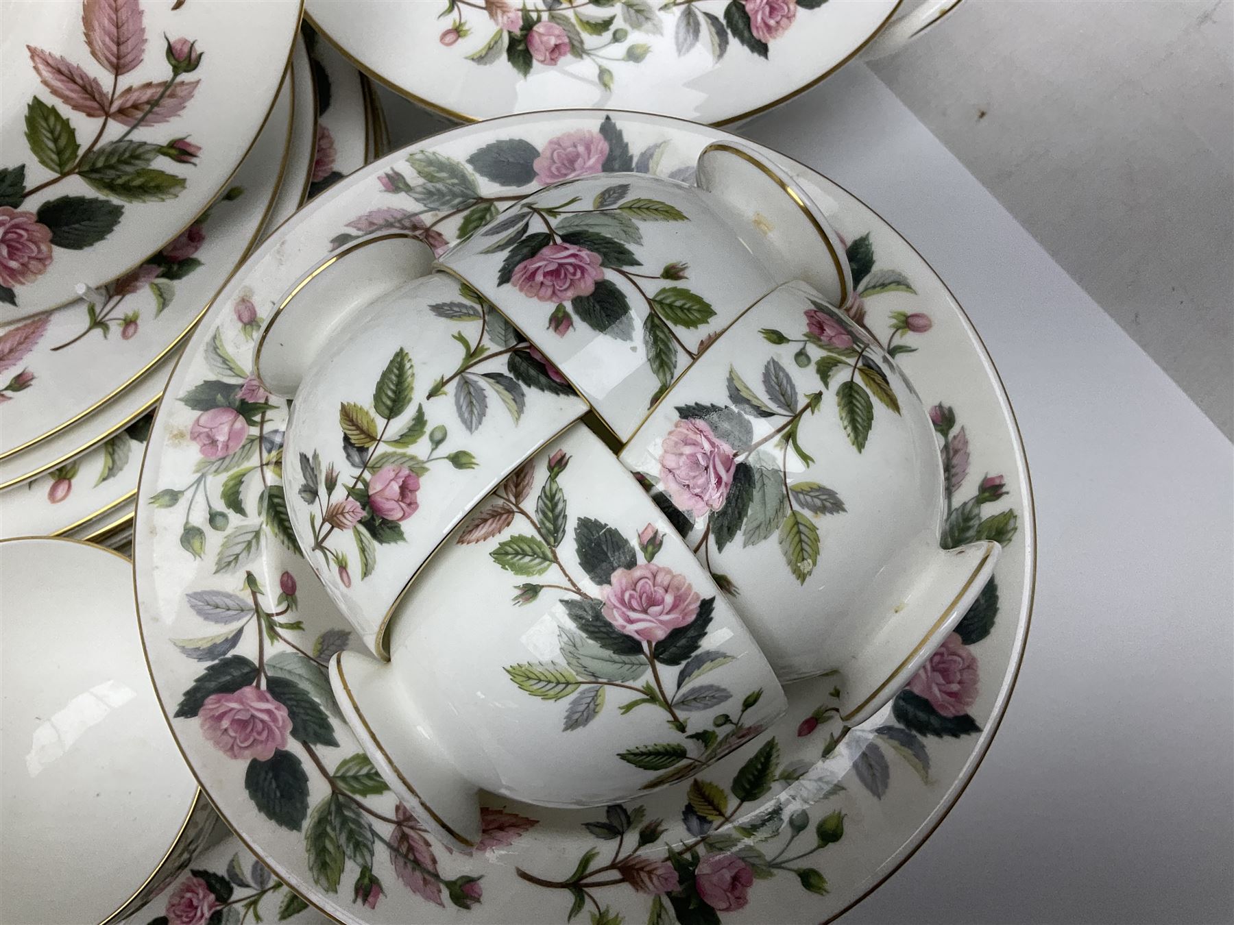 Wedgwood Hathaway Rose pattern tea and dinner wares, comprising twelve saucers, sixteen teacups, twenty tea plates, jug, sucrier, thirteen shallow bowls, sauce boat and saucer, two lidded tureens, larger jug, ten dinner plates, nine smaller plates and two large oval serving dishes