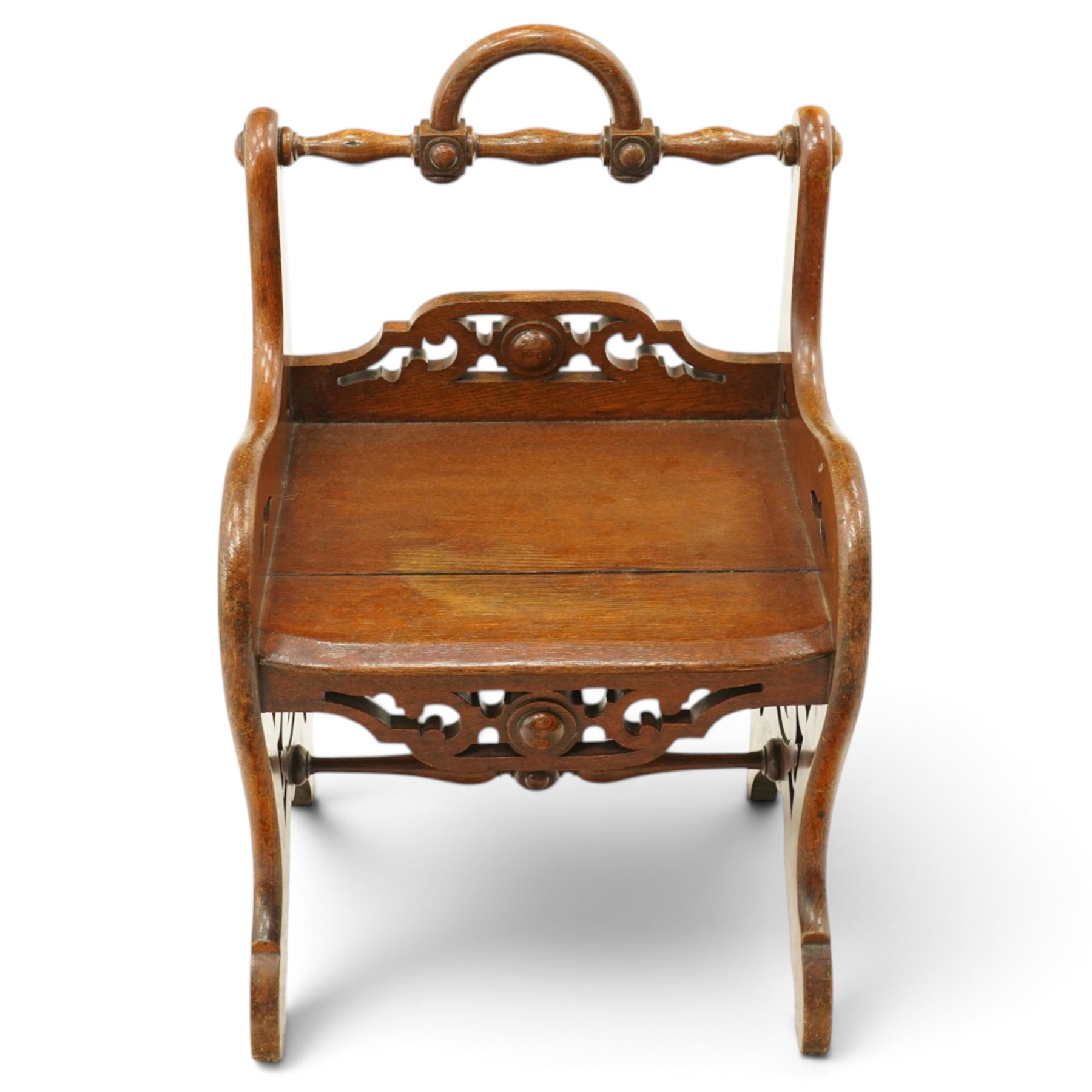 Late 19th century Gothic Revival carved oak hall chair or window seat, the swell-turned top rail centred by an arched carrying handle, over shaped open arms and solid plank seat, with pierced and carved scrolling foliate fretwork side panels and apron with applied central roundel, raised on shaped supports united by turned stretcher