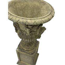 Pair of classical design cast stone Campana-shaped garden urns, the foliage moulded rim over the main body decorated with figural festive scenes, gadrooned underbelly with mask handles, foliate moulded moulded foot, raised on square pedestals with recessed panels and stepped moulded skirt