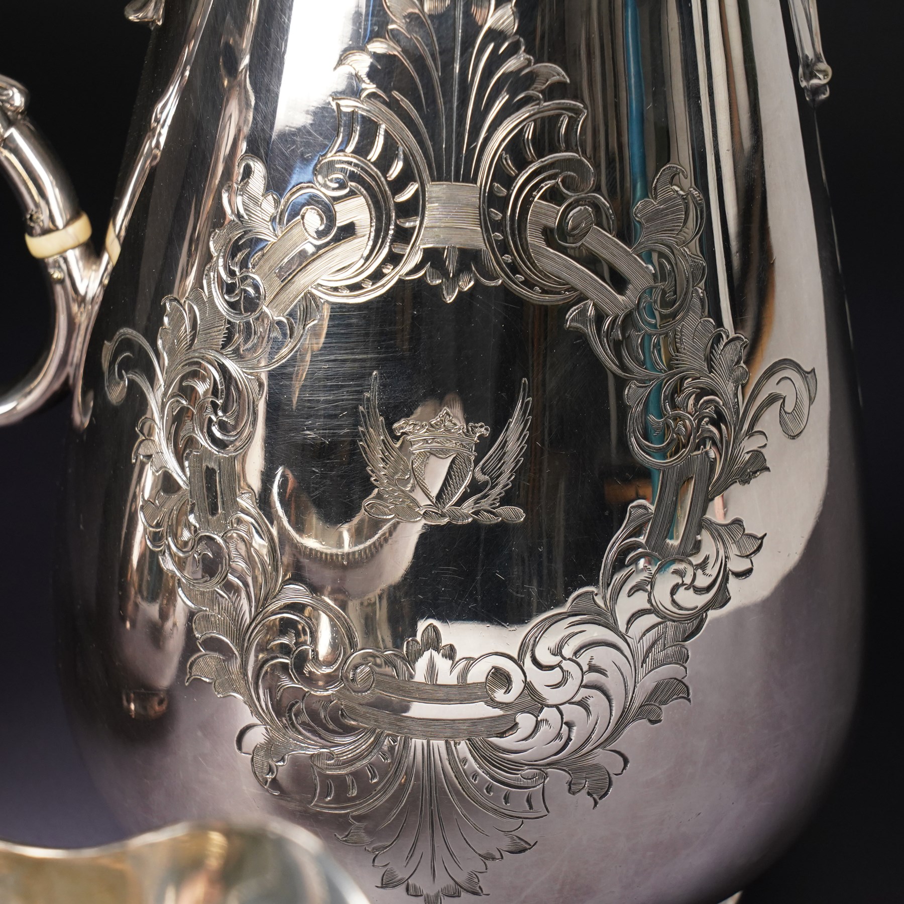 Pair of large silver plated sauce boats with bead edge decoration and C scroll handles engraved with a crest in the form of a winged heart and on shaped supports L20cm Maker probably Hawksworth Eyre & Co and an engraved hot water jug and a matching smaller jug with the same crest and by the same maker
