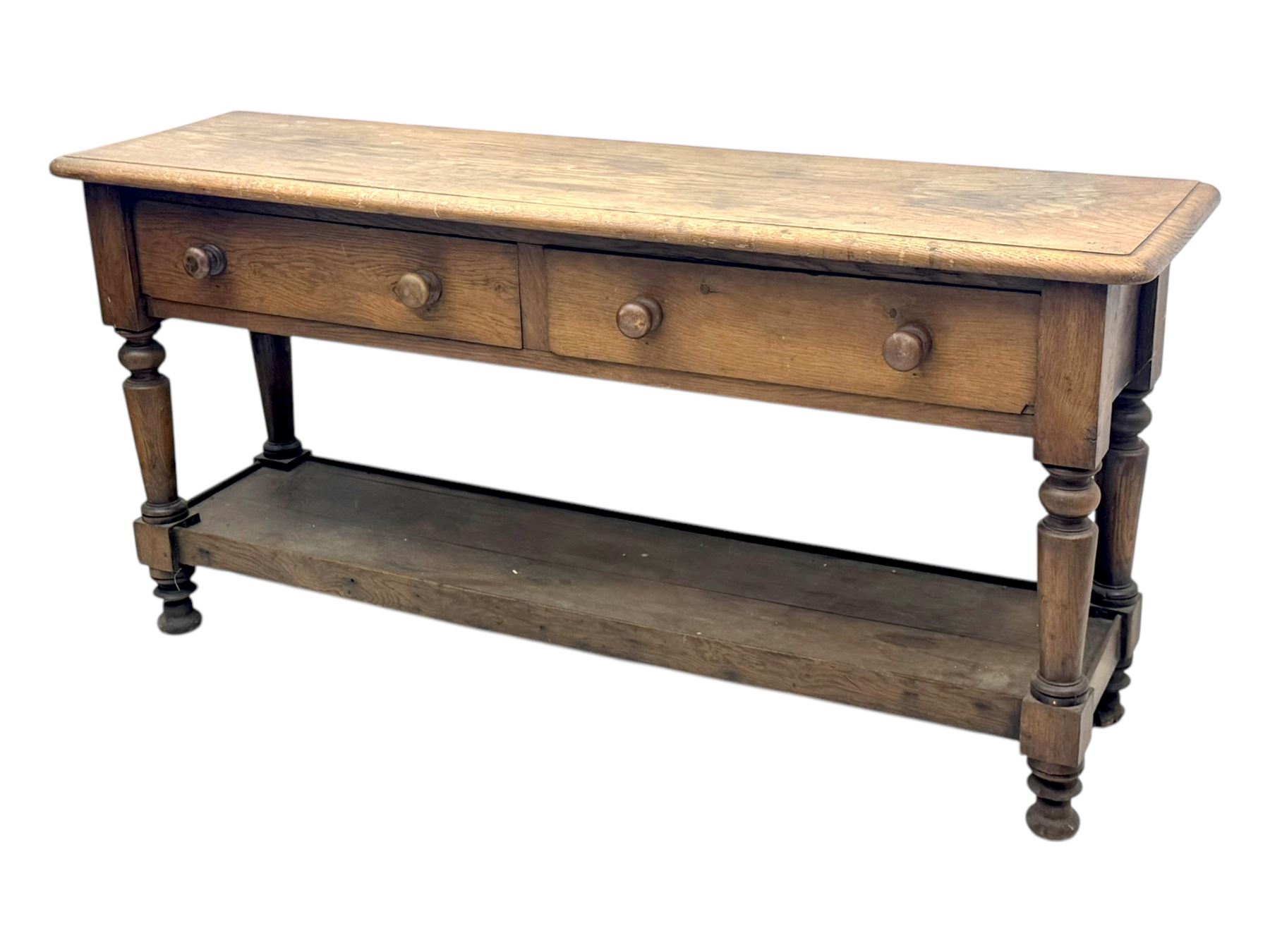 Late 19th century oak potboard dresser base, rectangular top over two frieze drawers with turned wooden handles, raised on four ring turned and tapering supports with block feet, united by a full-width lower potboard