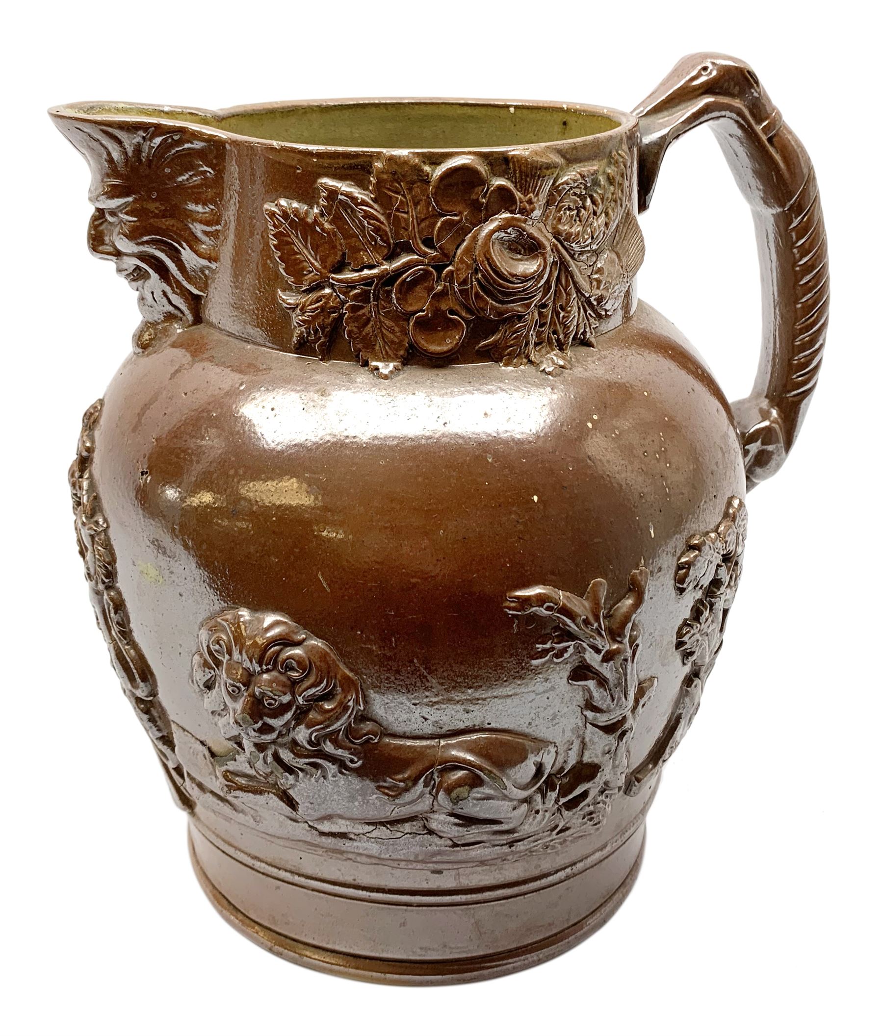 19th century salt glazed stoneware jug, with mask spout and greyhound modelled handle, the body decorated in relief with Royal Coat of Arms flanked by lions, the rim with the flowers of the union, roses, thistles and shamrocks, H26.5cm