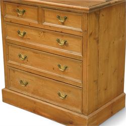 Early 20th-century pine gun cabinet with later fitted shelves, of two-part construction, upper cupboard moulded and dentil cornice above two panelled doors revealing three removable shelves and circular recesses for gun barrels at the top, lower section with two short and three long graduated drawers with brass swan neck handles on plinth base 