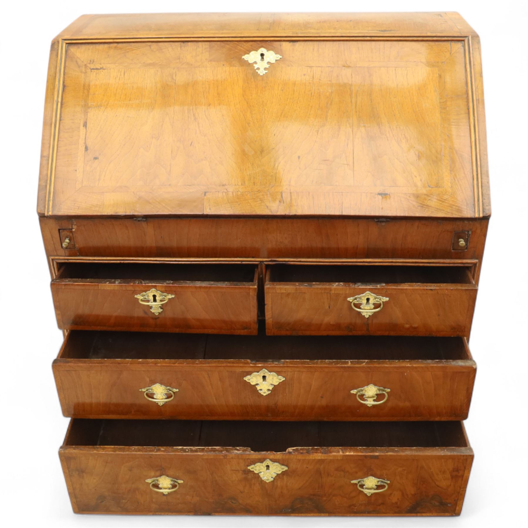 18th century walnut and herringbone banded bureau, the fall front enclosing a stepped and arched interior fitted with pigeonholes, drawers and concealed compartments, green tooled leather writing surface, over two short and three long graduated drawers with brass escutcheons and bail handles, shaped bracket feet
