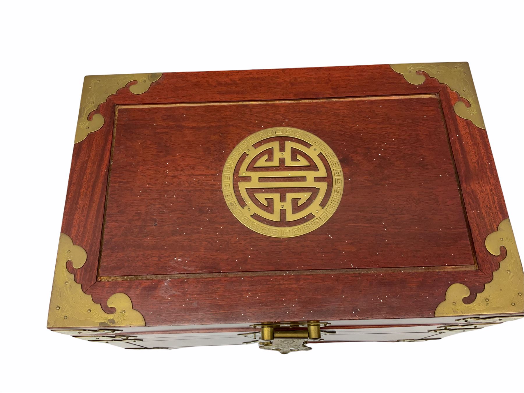 Chinese hardwood jewellery box mounted with engraved brass fixtures, the two exterior doors revealing three drawers below the hinged upper lid, lined with red material decorated with floral sprays, H25cm, W36cm, D23cm