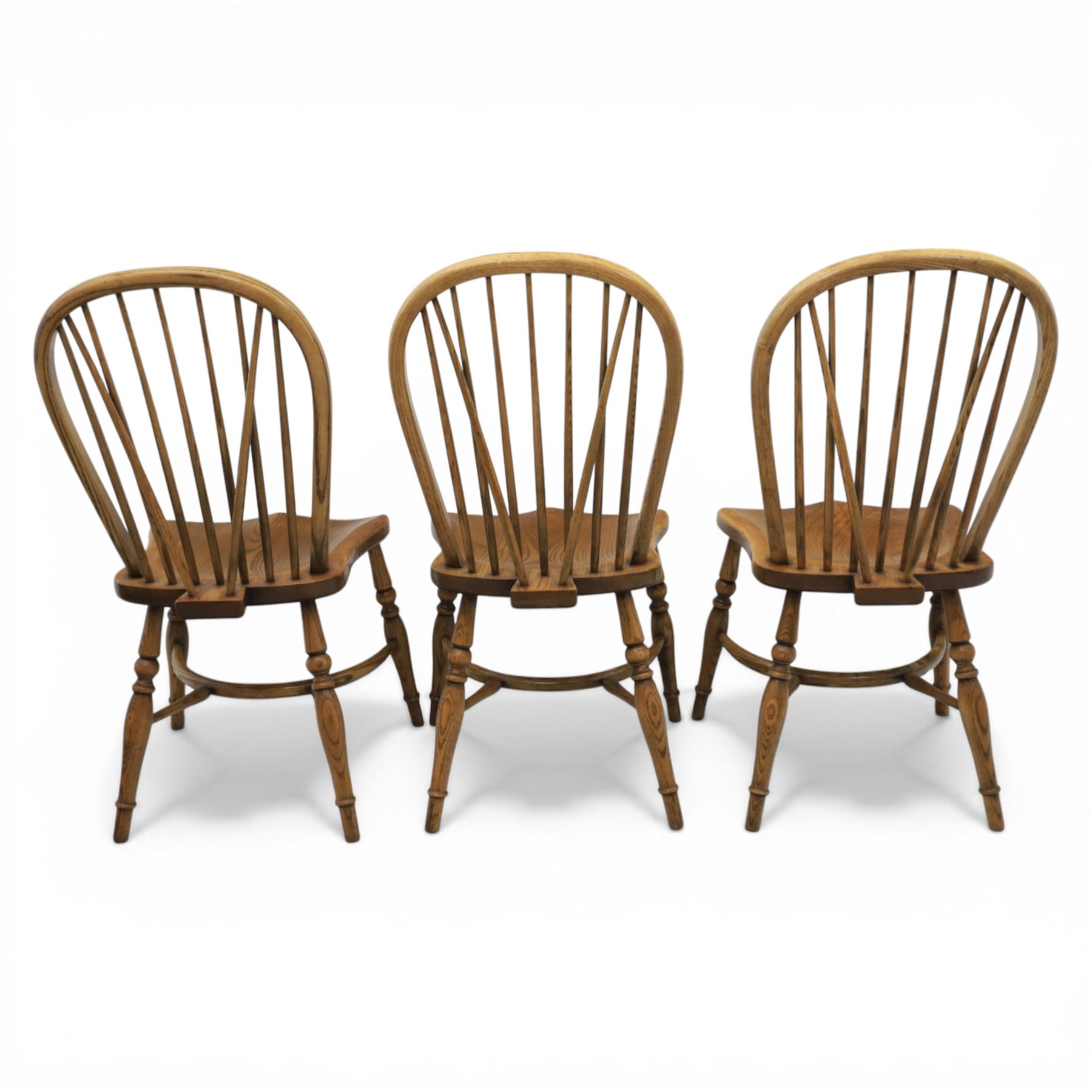 Traditional elm and beech Windsor dining chairs, each with hoop back and turned spindles over a shaped solid seat fitted with loose floral upholstered cushions, raised on turned tapering supports united by crinoline stretchers