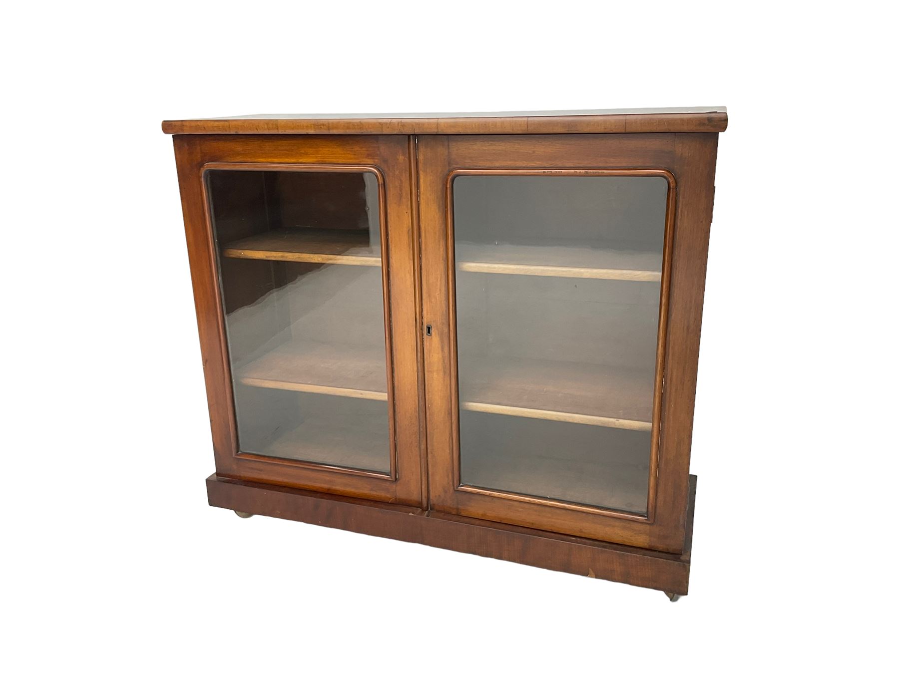 Victorian bookcase, rectangular top over two glazed doors enclosing two shelves, on skirted base