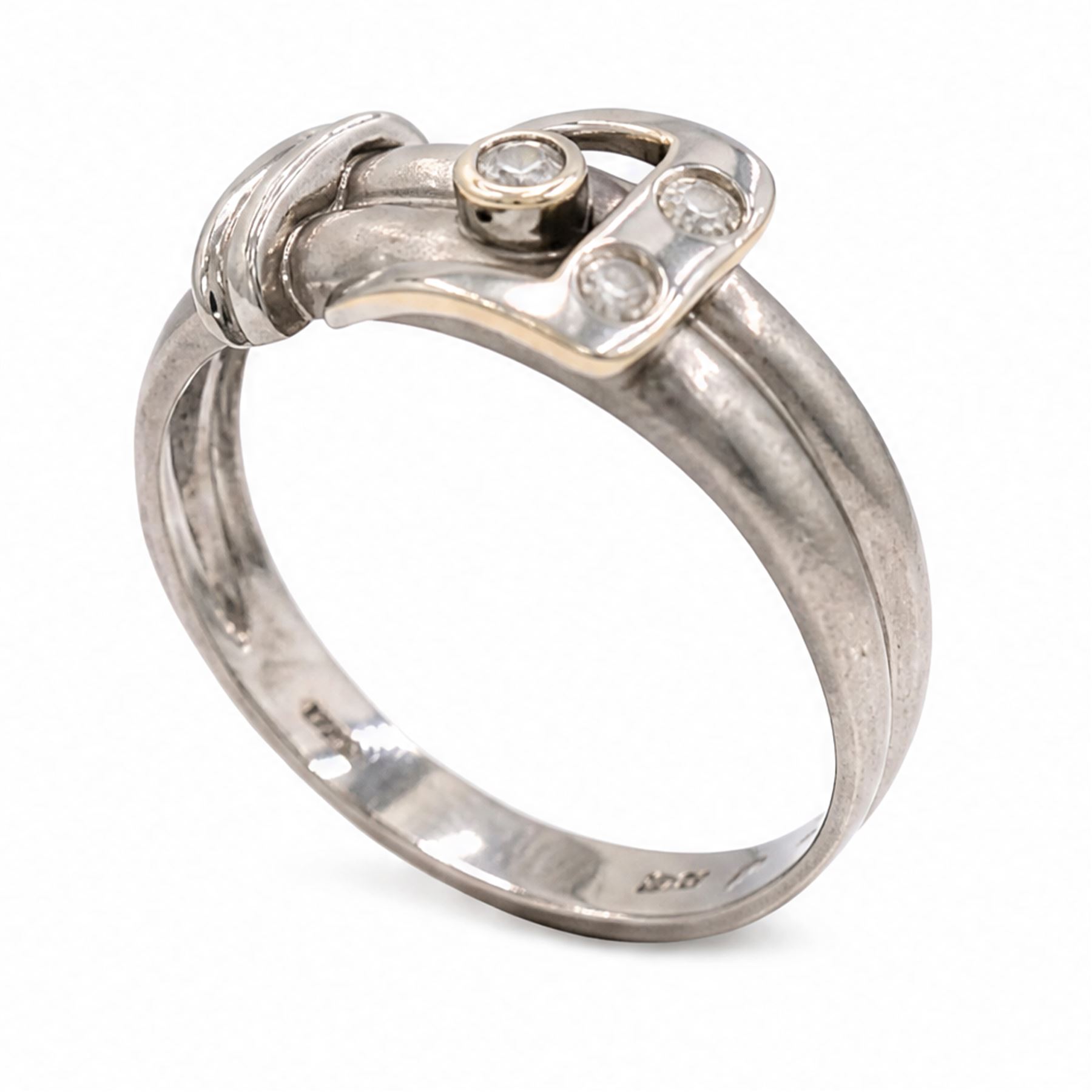 14ct white gold three stone diamond buckle ring, bezel and rubover set with three round brilliant cut diamonds, to a brushed and polished gold band, stamped 585