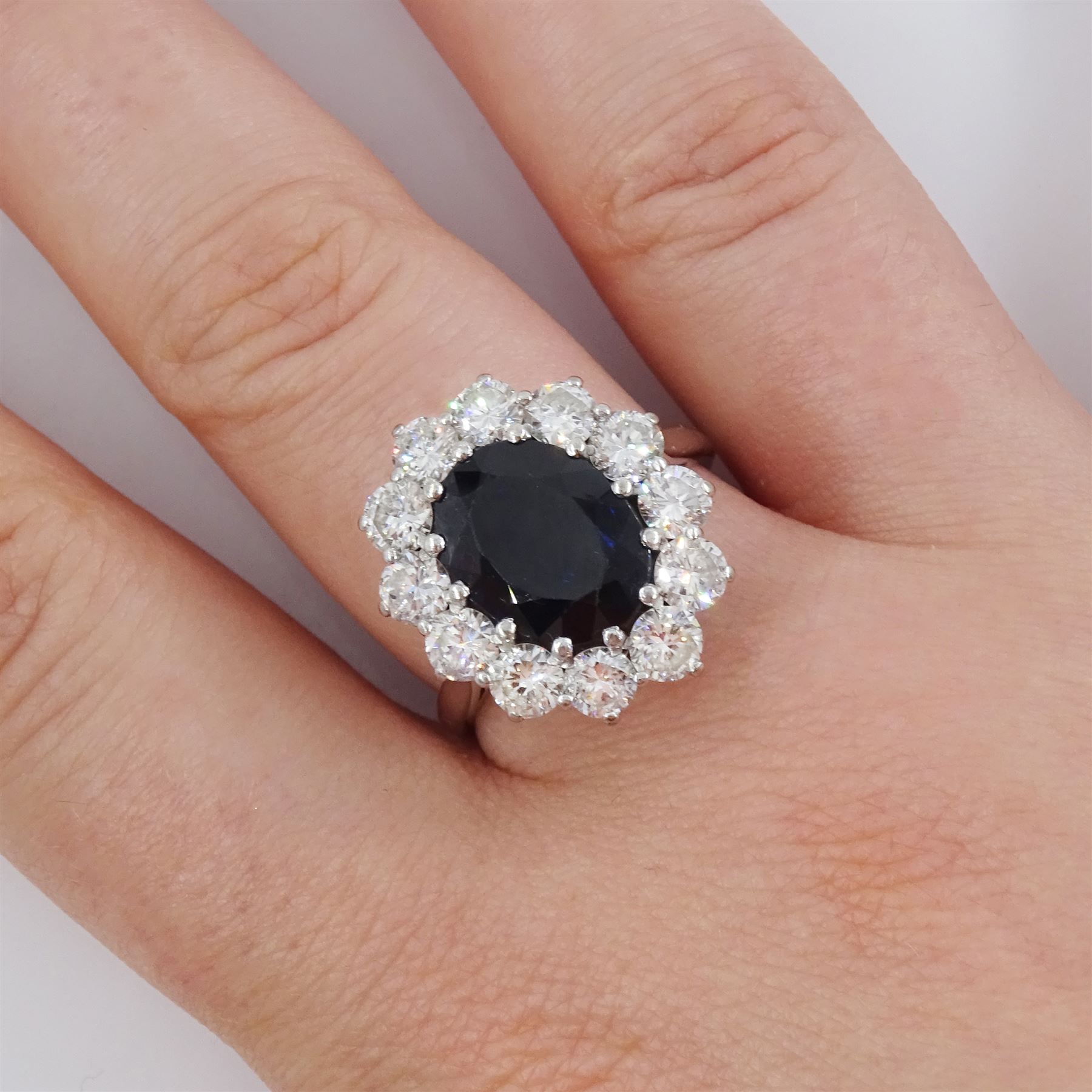 18ct white gold sapphire and diamond cluster ring, single oval cut sapphire of approx 4.50 carat, surrounded by twelve brilliant cut diamonds, Birmingham 1982, total diamond weight approx 2.65 carat