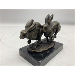 Bronze figure group, modelled as two hares in chase, upon a naturalistic base signed Nick and with foundry mark, raised upon a rectangular marble base, overall H12cm. 