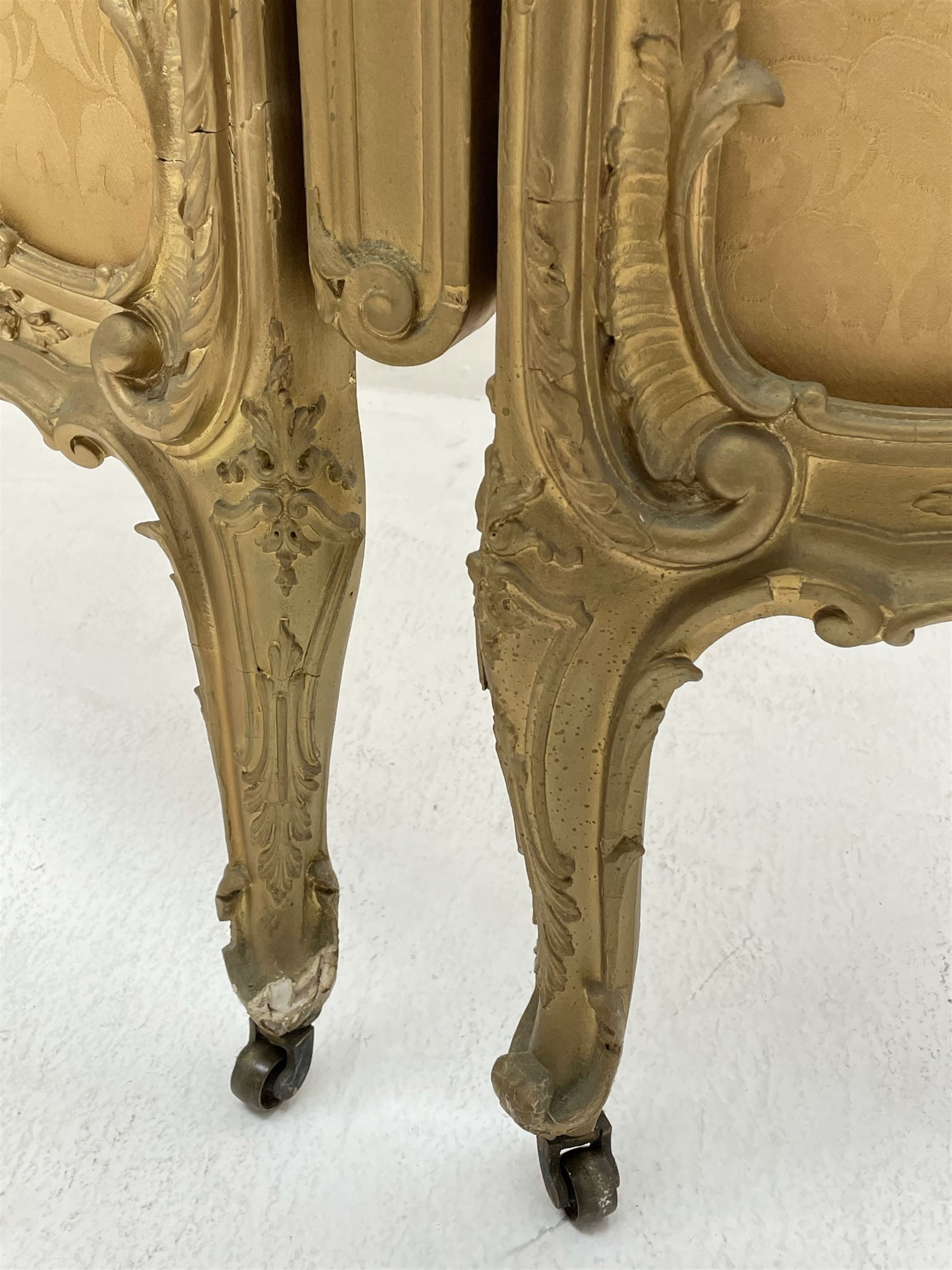 Late 19th/early 20th century French Rococo style gilt wood and gesso dressing screen, four double hinged panels, each with shaped cresting rail over shell and floral frieze, moulded frame with flower head and scroll decoration, acanthus leaf cabriole supports with castors, upholstered in gold Damask fabric
