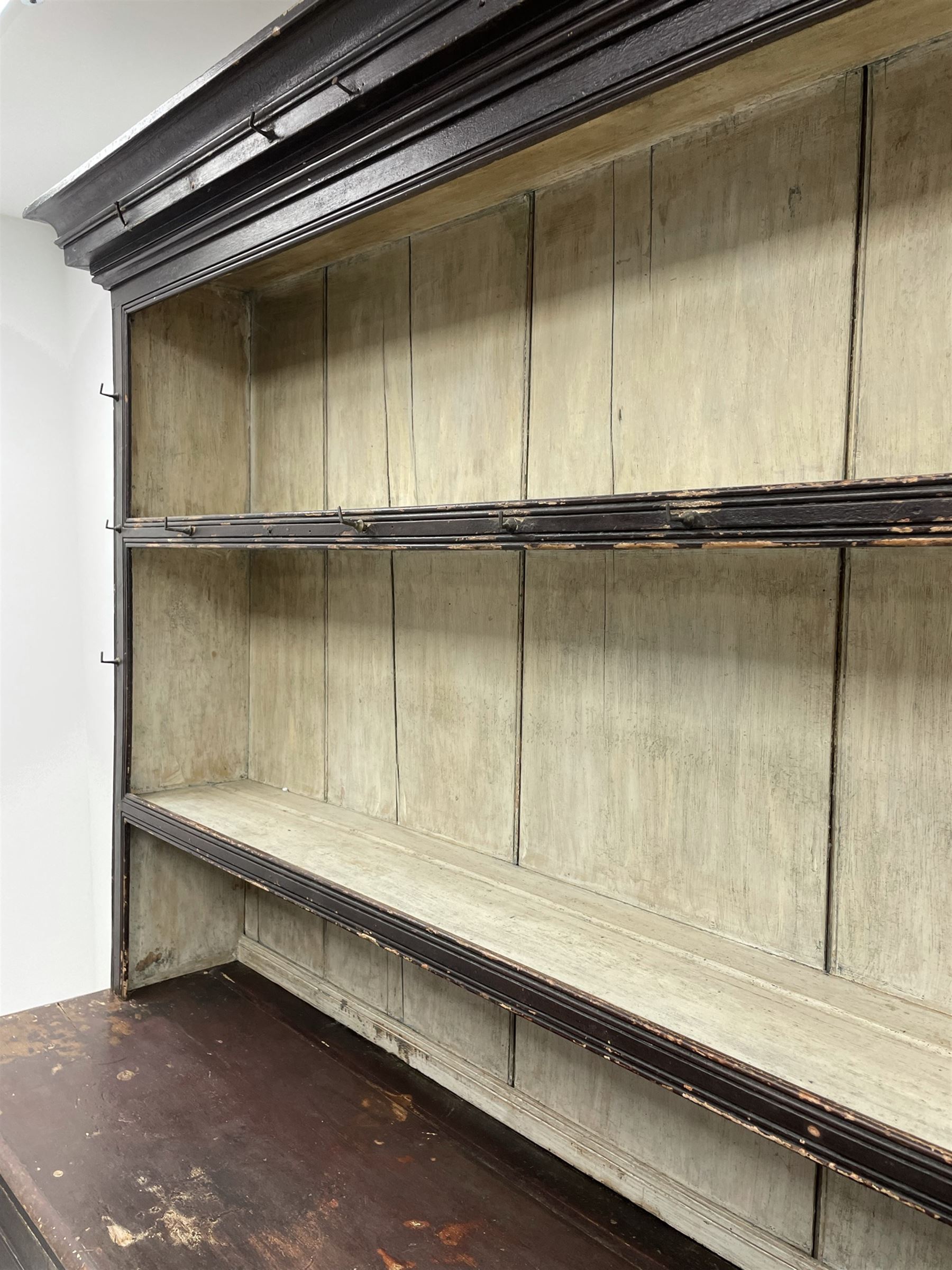 Early 19th century scumbled pine dresser, the projecting cornice over two heights plate rack with moulded frame, the base with reeded canted corners fitted with three drawers and two panelled cupboards, panelled sides, moulded skirt base