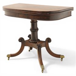 Early 19th century Regency mahogany fold over card table, the rounded rectangular top with brass line inlay enclosing green baize playing surface, crossbanded and strung exterior, with reeded edge above a gadrooned frieze, raised upon a turned column and four reeded sabre supports terminating in brass caps and castors